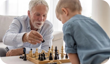 An older man playing chess with a child